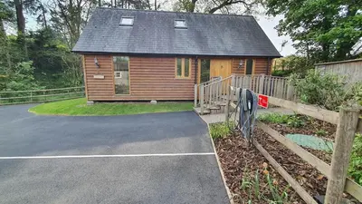 a log cabin with a driveway and a house at Swn Y Nant Lodge with hot tub Brecon in Brecon