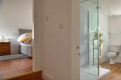 a glass shower in a bedroom with a bed at Finest Retreats - Moelis Barn in Llandrillo