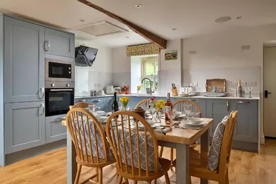 a kitchen with a wooden table and chairs in a kitchen at Finest Retreats - Moelis Barn in Llandrillo