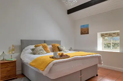 a bedroom with a large bed with a yellow blanket at Finest Retreats - Moelis Barn in Llandrillo