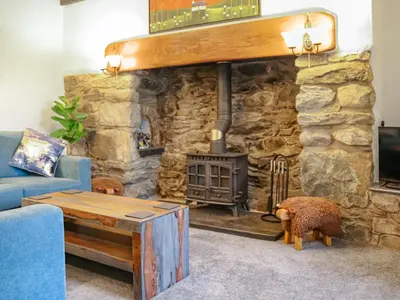 a living room with a stone fireplace and a blue couch at Hafanedd in Dyffryn