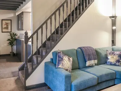 a living room with a blue couch next to a staircase at Hafanedd in Dyffryn