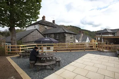 a person sitting at a picnic table with an umbrella at OYO Glyn Valley Hotel in Glyn-Ceiriog