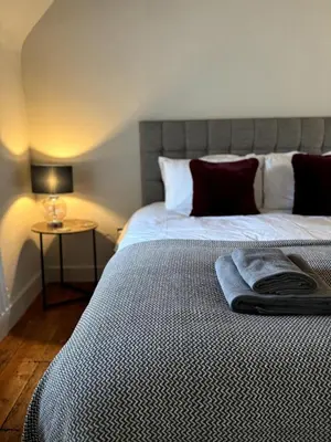 a bed with a black and white comforter and a table at The Cottage, Upper Linney, Ludlow in Ludlow