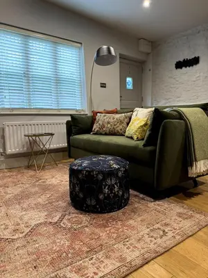 a living room with a green couch and a ottoman at The Cottage, Upper Linney, Ludlow in Ludlow
