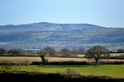 a green field with trees and hills in the background at Finest Retreats - Walton Maisonette in Onibury