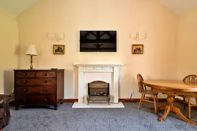 a living room with a table and a fireplace at Finest Retreats - Walton Maisonette in Onibury