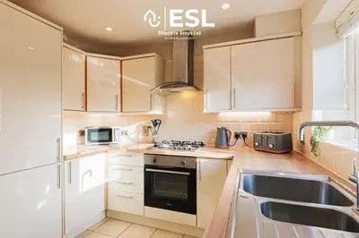 a kitchen with white cabinets and a sink at 4 bedroom house in Shrewsbury with parking in Shrewsbury