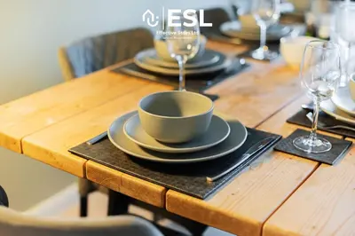 a wooden table with plates and wine glasses on it at 4 bedroom house in Shrewsbury with parking in Shrewsbury