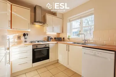 a kitchen with white cabinets and a sink at 4 bedroom house in Shrewsbury with parking in Shrewsbury