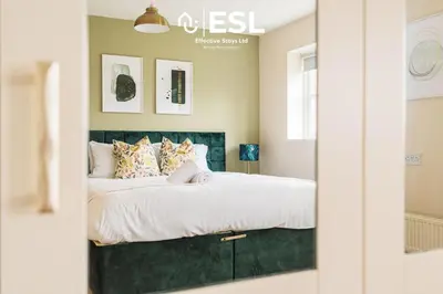 a bedroom with a bed with a green headboard at 4 bedroom house in Shrewsbury with parking in Shrewsbury