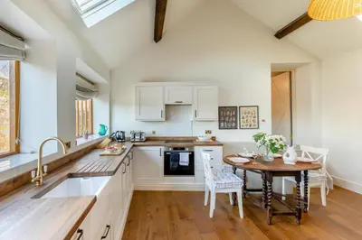 a kitchen with white cabinets and a wooden table at 2 Bed in Llangedwyn oc-l30530 in Llangedwyn