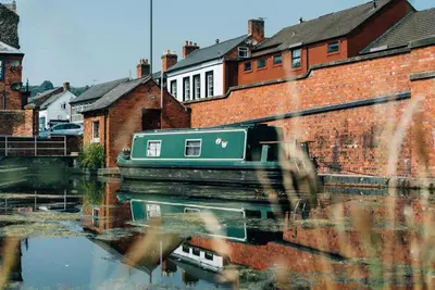 a green boat on a river next to buildings at 2 Bed in Llangedwyn oc-l30530 in Llangedwyn