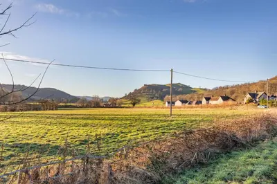 a field of grass with houses in the background at 2 Bed in Llangedwyn oc-l30530 in Llangedwyn