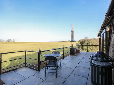 a patio with two chairs and a table and a fence at GWR Wagon - Victoria Station in Craven Arms