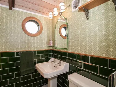a green tiled bathroom with a sink and a mirror at GWR Wagon - Victoria Station in Craven Arms