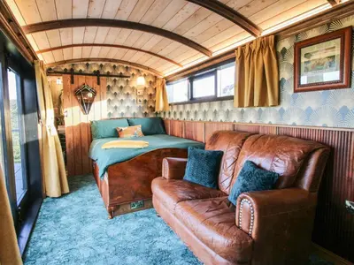 a room with a couch and a bed in a train at GWR Wagon - Victoria Station in Craven Arms
