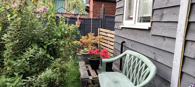 a green bench sitting next to a house with plants at Robins nest in Great Hanwood