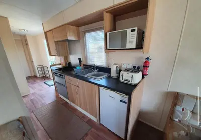 a small kitchen with a stove and a microwave at Pet Friendly 3 Bed Static Caravan in Clarach Bay Spacious and Cozy Stay in Aberystwyth