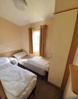 a small room with two beds and a window at Pet Friendly 3 Bed Static Caravan in Clarach Bay Spacious and Cozy Stay in Aberystwyth