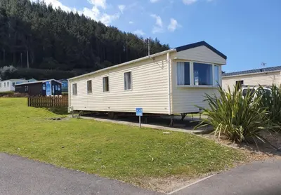 a mobile home is parked in a yard at Pet Friendly 3 Bed Static Caravan in Clarach Bay Spacious and Cozy Stay in Aberystwyth