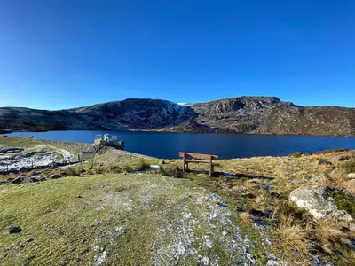 a bench sitting on the side of a lake at Golygfa'r Orsaf Snowdonia national park, Bala lake in Bala