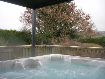 a jacuzzi tub in a backyard with a fence at Bevan House with Hot Tub in Mid-Wales in Hundred House