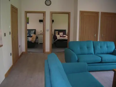 a living room with a blue couch and a bedroom at River Lodge Hot Tub Sleeps 6 in Hundred House