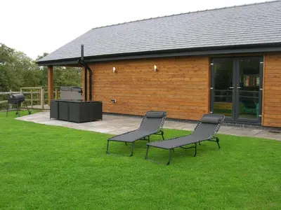 three chairs sitting in the grass in front of a building at River Lodge Hot Tub Sleeps 6 in Hundred House
