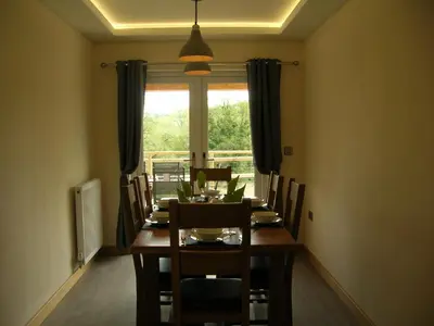 a dining room with a table and chairs and a window at Woodland Lodge Hot Tub Sleeps 6 in Hundred House