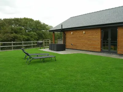 a bench sitting in the grass next to a building at Woodland Lodge Hot Tub Sleeps 6 in Hundred House