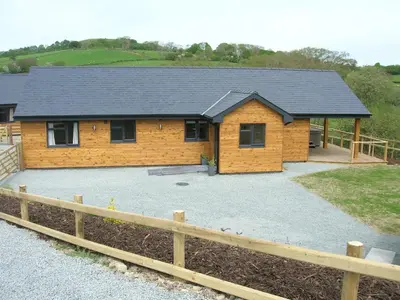 a log cabin with a driveway in front of it at Woodland Lodge Hot Tub Sleeps 6 in Hundred House