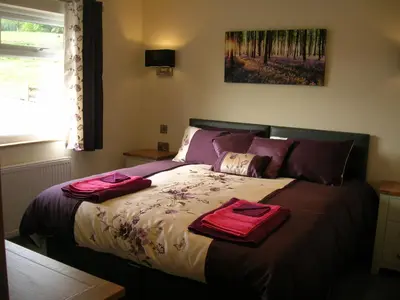 a bedroom with a bed with two towels on it at Woodland Lodge Hot Tub Sleeps 6 in Hundred House
