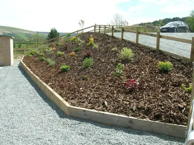 a raised garden with plants in a fence at Woodland Lodge Hot Tub Sleeps 6 in Hundred House