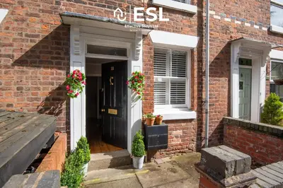 a brick house with a black door and flowers at 2 Bed Townhouse with Garden & Parking in Shrewsbury