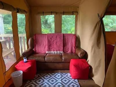 a living room with a leather couch in a tent at Cefn Crib Safari Tent in Machynlleth