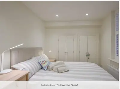 a white bedroom with a large bed with two pillows at Westhaven 5 Beachfront Luxury-Free parking permit in Aberdyfi