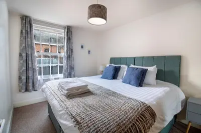 a bedroom with a large bed with blue pillows and a window at 2 bedroom apartment - Shrewsbury town centre in Shrewsbury