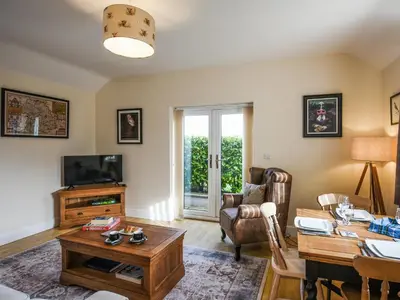 a living room with a table and a tv at The Old Milking Parlour in Melverley