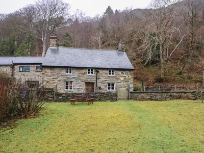 an old stone house with a bench in front of it at Tafarn Trip in Blaenau-Ffestiniog