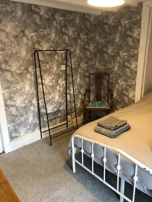 a bedroom with a bed and a chair and a wall at The Eagles Inn in Rhayader