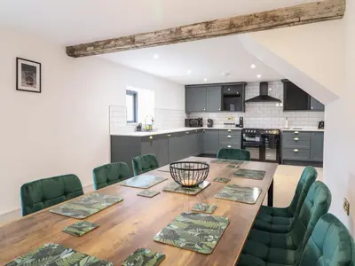 a kitchen and dining room with a wooden table and green chairs at Sally's Barn in Oswestry