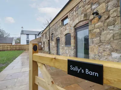 a sign on a wooden bench in front of a building at Sally's Barn in Oswestry