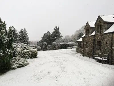a snow covered road in front of a house at Detached cottage in the hills near Dolgellau in Cross Foxes