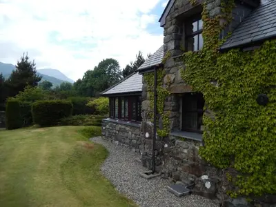 a stone house with ivy on the side of it at Detached cottage in the hills near Dolgellau in Cross Foxes