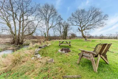 two picnic tables in a field next to a stream at 1 Bed in Drefach oc-m30848 in Llanwenog