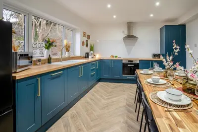 a kitchen with blue cabinets and a wooden table at 4 Bed in Brecon oc-h30823 in Brecon
