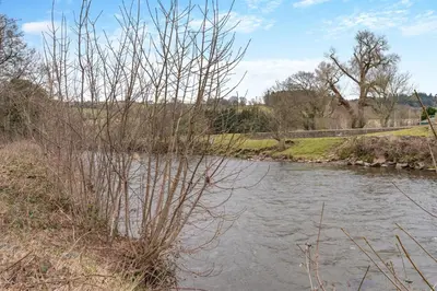 a river with trees and a bridge in the background at 4 Bed in Brecon oc-h30823 in Brecon