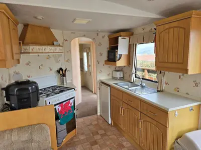 a small kitchen with a stove and a sink at Homely 2 Bedrommed Mobile Home E1 in Aberystwyth