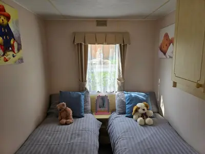 two teddy bears sitting on beds in a bedroom at Homely 2 Bedrommed Mobile Home E1 in Aberystwyth